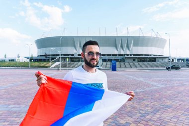 Onun beyaz T-shirt ve şort sakallı genç bir adam rüzgarda gelişmekte olan Rusya bayrağı tutuyor