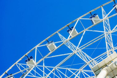 İnsanlar için rahat kabinleri ile yeni uzun boylu beyaz dönme dolap yavaş yavaş açık mavi gökyüzü karşı büyük bir şehir merkezinde bir daire içinde döndürme