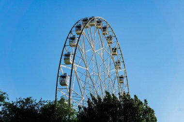 İnsanlar için rahat kabinleri ile yeni uzun boylu beyaz dönme dolap yavaş yavaş açık mavi gökyüzü karşı büyük bir şehir merkezinde bir daire içinde döndürme