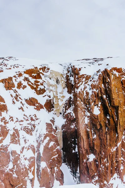 Wysokie Skały Czerwony Wzrośnie Powyżej Pokrytych Śniegiem Wybrzeża Morza Zimą — Zdjęcie stockowe