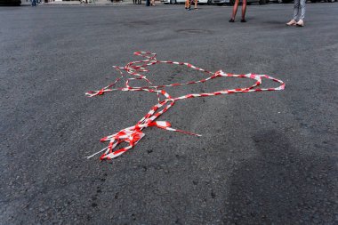 Kırmızı beyaz koruyucu bant rüzgar tarafından küçük bir kitle bir tatil sırasında ayak passer asfalt yol üzerinde altında yalan söylüyor