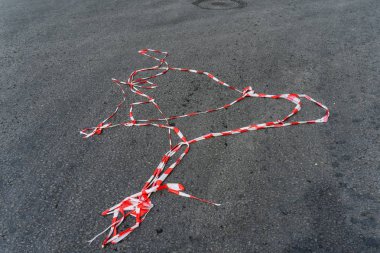 Kırmızı beyaz koruyucu bant rüzgar tarafından küçük bir kitle bir tatil sırasında ayak passer asfalt yol üzerinde altında yalan söylüyor