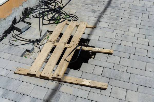 A deep pit in the middle of the new pavement is covered by old unreliable boards