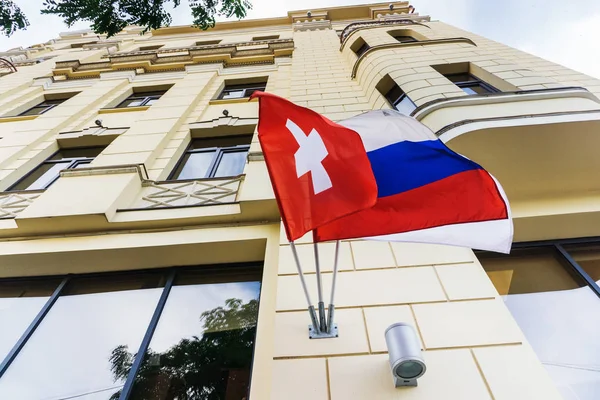 On the wall of the hotel in a beautiful old building flags of Russia and Switzerland develop during a joint meeting of the two countries