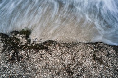 Yağlanmış küçük dalgalar ile uzun pozlama için fotoğraflandı bir deniz tatil sahilde karanlık deniz kıyısında akşam fırtına başlangıcı sırasında köpük