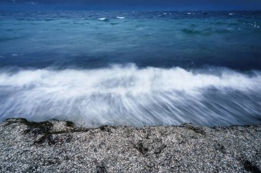 Yağlanmış küçük dalgalar ile uzun pozlama için fotoğraflandı bir deniz tatil sahilde karanlık deniz kıyısında akşam fırtına başlangıcı sırasında köpük