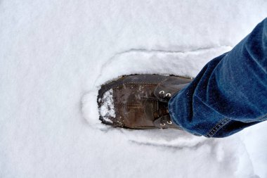 Bacağına kot üzerine giyilen bir kahverengi ayakkabı kar soğuk kuzey kış aylarında düştü.