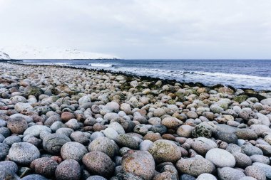 Kuzey Buz Denizi kutup soğuk kış gününde beyaz kar altında mavi soğuk su kıyısında büyük yuvarlak taş