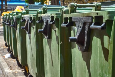 yeşil plastik çöp tenekeleri stand uzun boylu bir Konut Binası yakınındaki cadde boyunca bir sürü