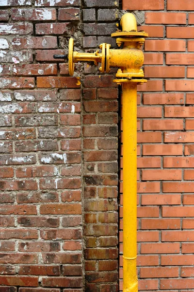 石の壁に家に家庭用ガス供給のラウンド タップ古い黄色のガス管色の夏の日に通りの建物 — ストック写真