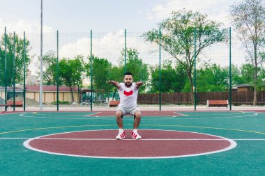 beyaz spor gömlekli sakallı genç bir adam fiziksel eğitim kas ve sağlık açık bir oyun üzerinde bir sıcak yaz gününde güçlendirmek için devreye girer