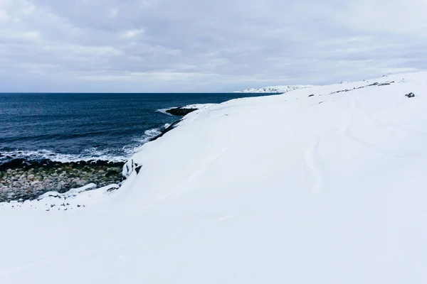 冬の凍るような日の雪で覆われた北の青い冷たい海の岩の海岸 — ストック写真