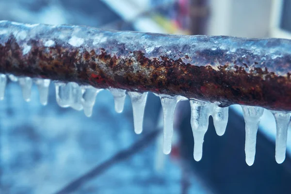 stock image Many small icicles have frozen on a rusty pipe in the street in the winter