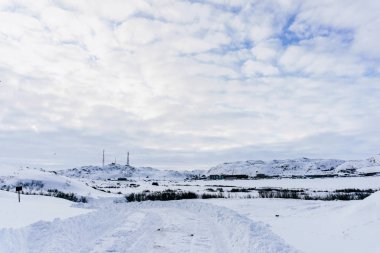 Karla kaplı viraj yolu, kışın Kuzey Kutup Dairesi 'nin kuzeyindeki köyün yakınındaki cep telefonuyla telsiz kulesine çıkıyor.