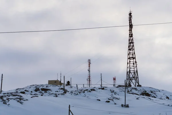 在北极圈以外的一个偏远的北方村庄里 冬季被雪覆盖的小山上的无线电手机塔楼 — 图库照片
