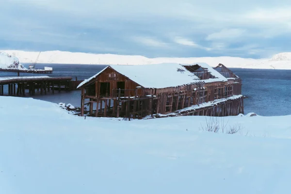 冬天在俄罗斯北部的一个小海湾里 雪下废弃的木制系泊装置 — 图库照片