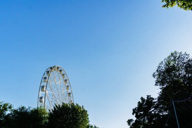 İnsanlar için rahat kabinleri ile yeni uzun boylu beyaz dönme dolap yavaş yavaş açık mavi gökyüzü karşı büyük bir şehir merkezinde bir daire içinde döndürme