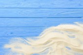 Písek vlny na modré dřevěné pozadí