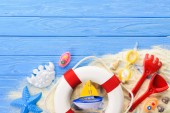 Rettungsring und Strandspielzeug auf blauem Holzhintergrund