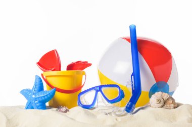 Diving mask with beach ball and toys in sand isolated on white clipart