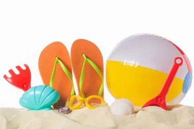 Beach ball and flip flops in sand isolated on white clipart
