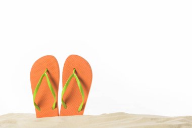 Pair of flip flops in sand isolated on white clipart