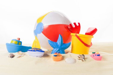 Beach ball and kid toys in sand isolated on white clipart