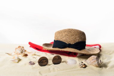 Hasır şapka ve güneş gözlüğü kabukları üzerinde beyaz izole kum ile