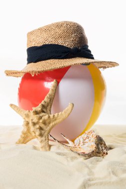 Plaj topu üzerinde beyaz izole kum deniz kabuğu tarafından hasır şapka altında