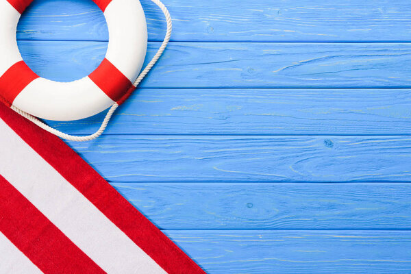 Life ring with towel on blue wooden background