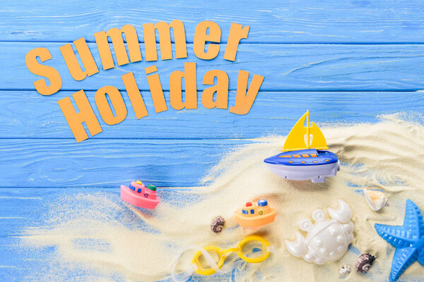 Beach toys by Summer holiday inscription on blue wooden background