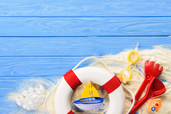 Life ring and toy boats on blue wooden background