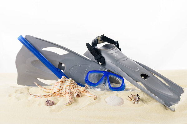 Flippers and dive mask in sand isolated on white