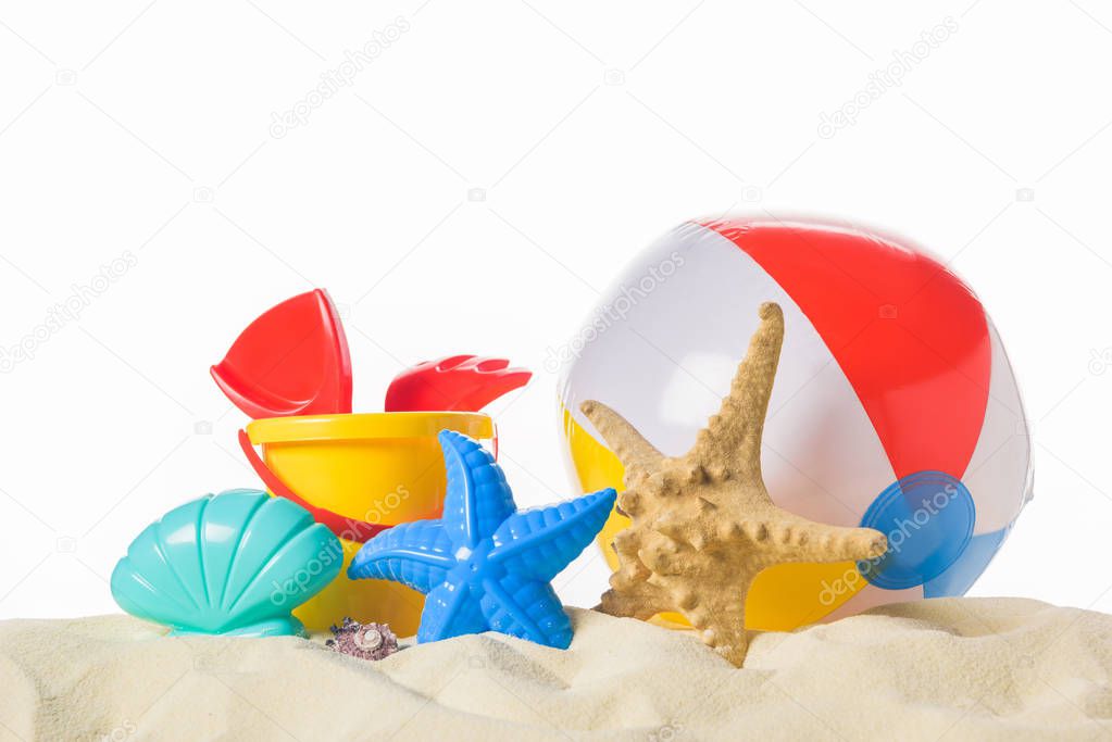 Beach ball and toys in sand isolated on white