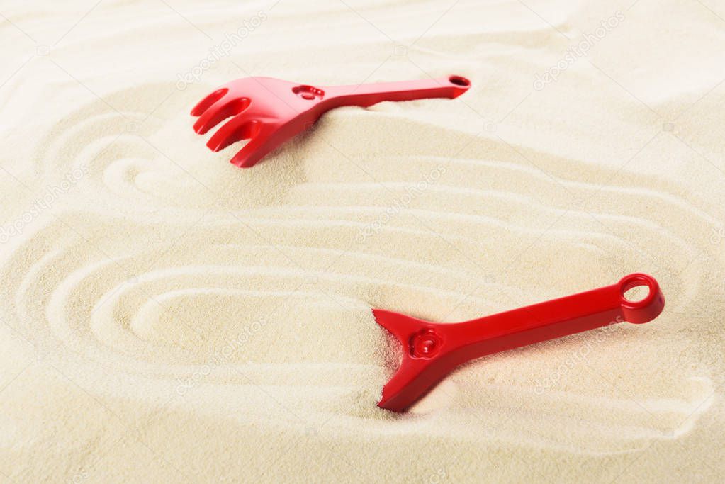 Toy shovel and rakes on sandy beach
