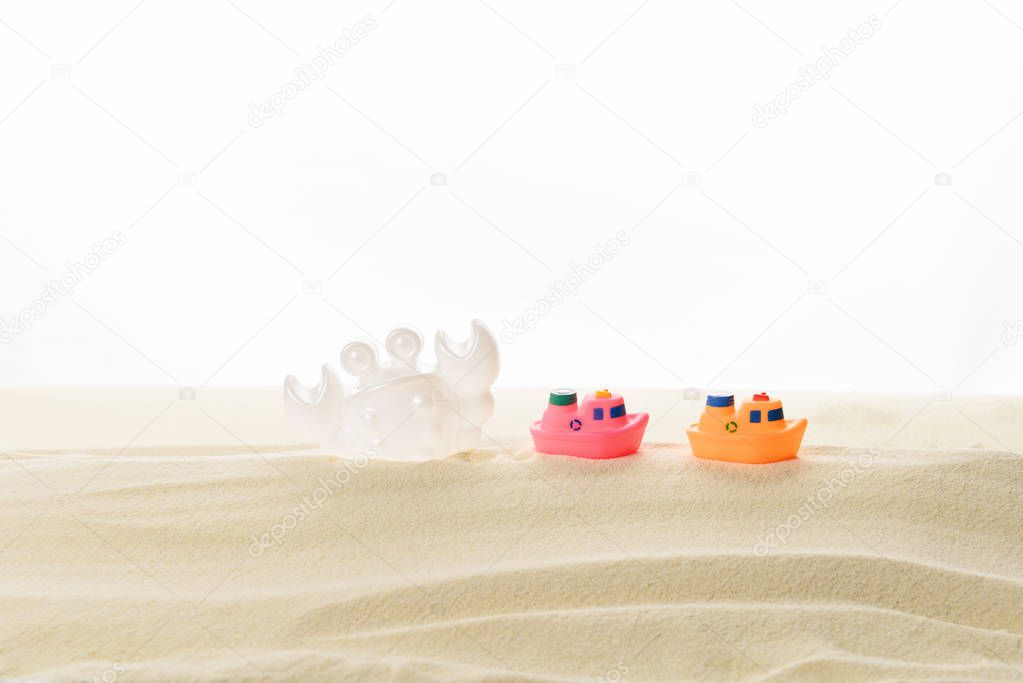 Toy boats and crab in sand isolated on white