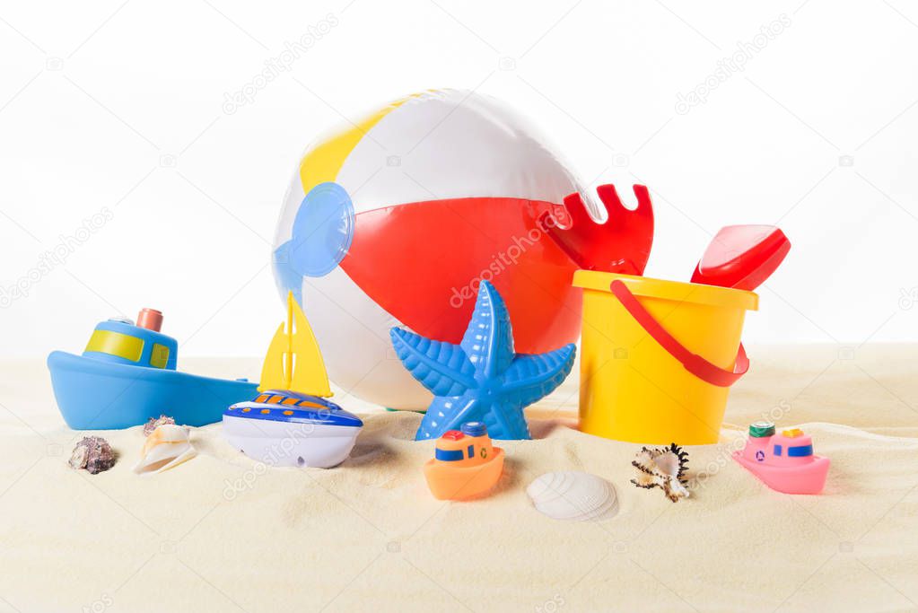 Beach ball and kid toys in sand isolated on white