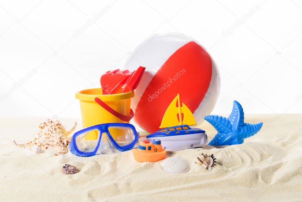 Beach ball and toys in sand isolated on white