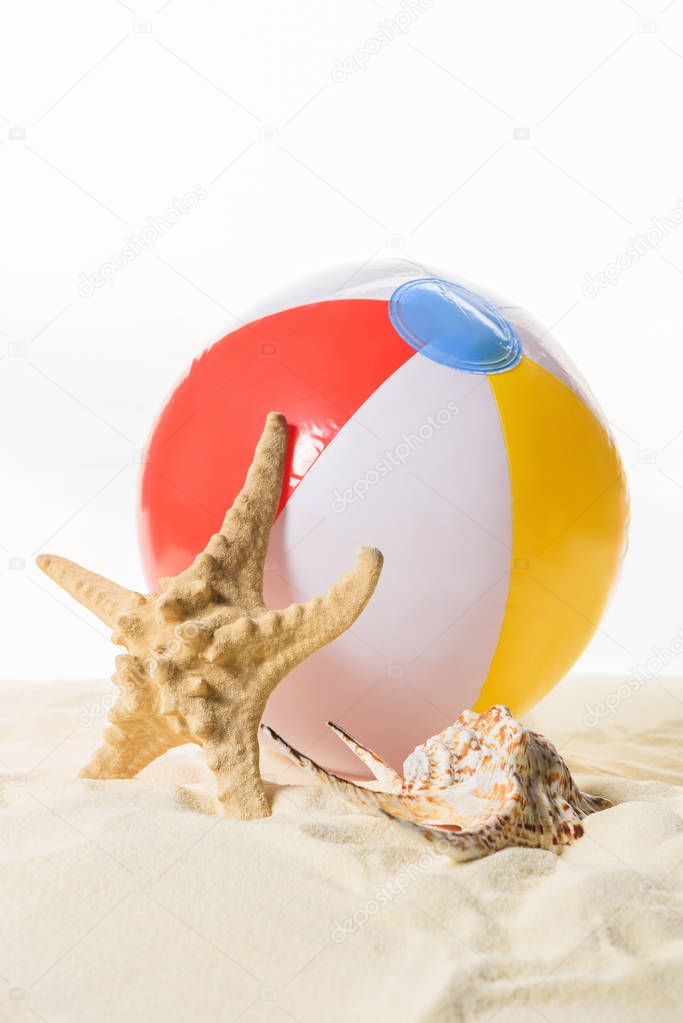 Beach ball and starfish in sand isolated on white