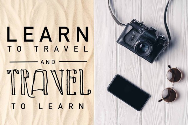 Смартфон с фотоаппаратом и солнцезащитными очками на пирсе на легком песке с надписью "научиться путешествовать и путешествовать, чтобы учиться"
