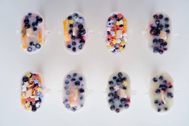 top view of tasty homemade popsicles with organic fruits and berries on grey  clipart