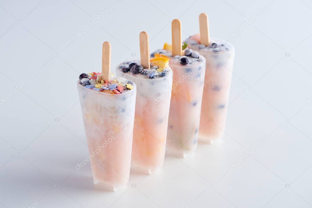 sweet homemade popsicles with fruits and berries in containers on grey  