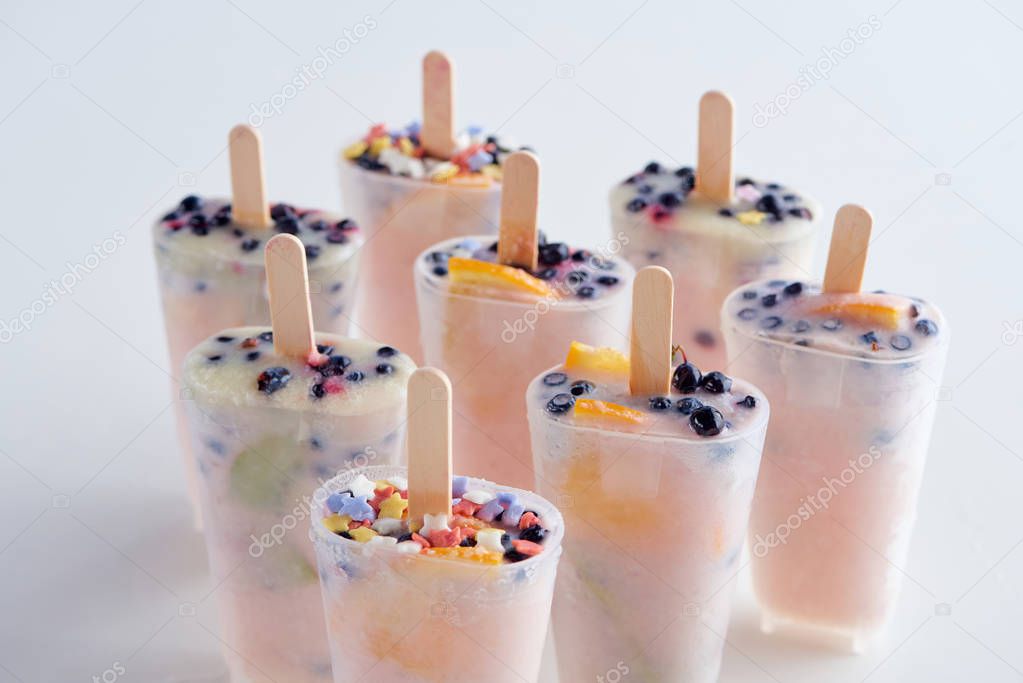 close-up view of tasty homemade popsicles with sticks in containers on grey  