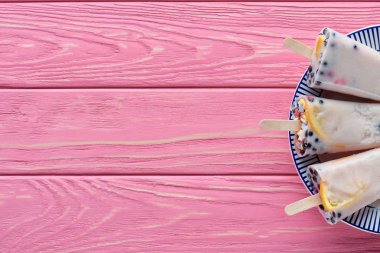 top view of sweet tasty homemade popsicles with fruits and berries on plate on pink wooden table  clipart