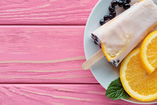 сверху вид на вкусное домашнее мороженое с фруктами и мятой на тарелке на розовом деревянном столе

