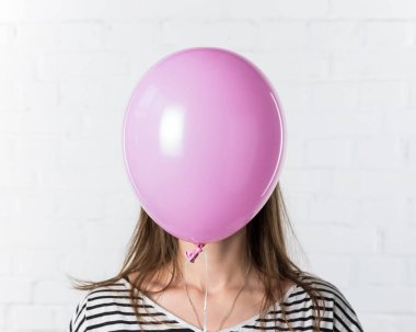 Pembe balon yüz beyaz tuğla duvar arka plan üzerinde genç kadının kapsayan