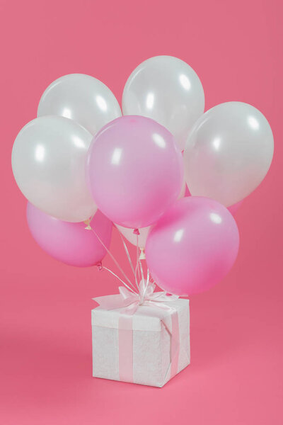 Подарки с белыми и розовыми шариками на розовом фоне

