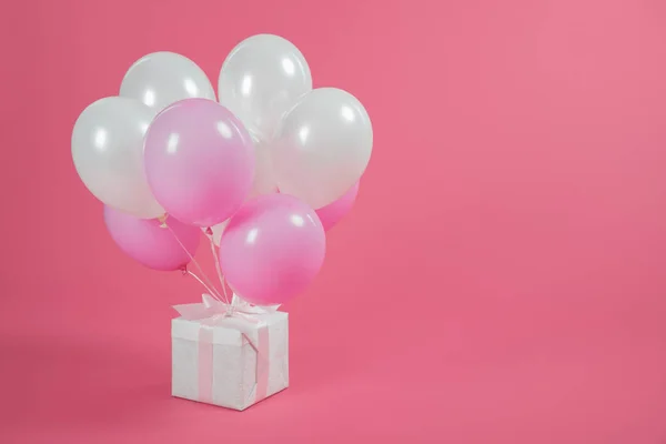 Gift box and balloons on pink background