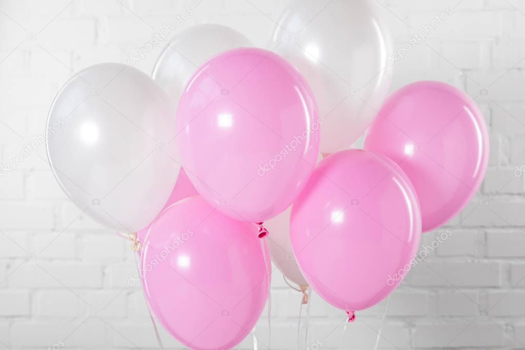 Pink and white party balloons on white brick wall background