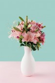 white vase with pink lily flowers on pastel background